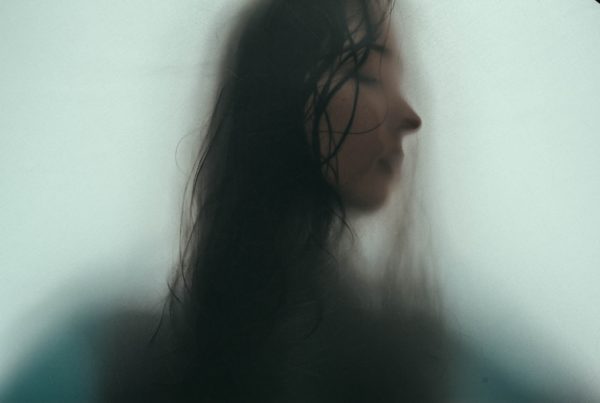 Silhouette of a woman's profile against foggy glass