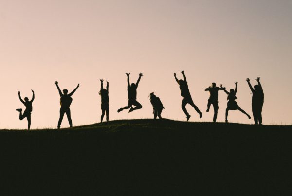 Silhouettes of various people jumping on a hillside