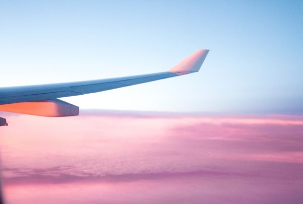 an airplane wing set against a backdrop of a beautiful blue sky and pink clouds