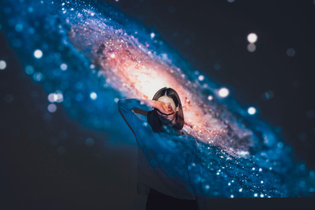a woman covering her face as a galaxy hologram covers her face