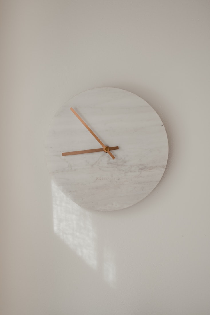 a marble clock with rose gold hands
