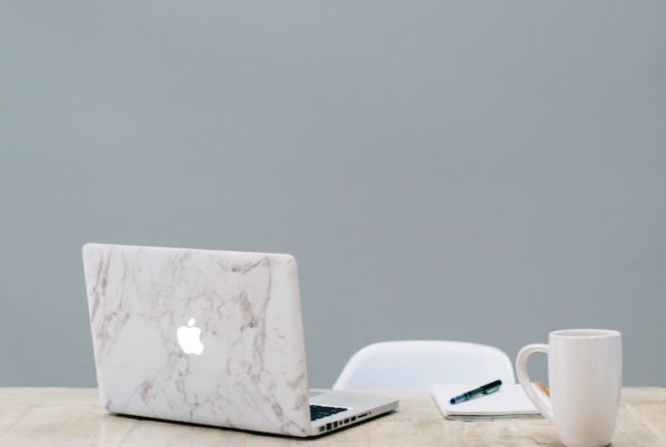 an elegant desk with a computer, journal and mug