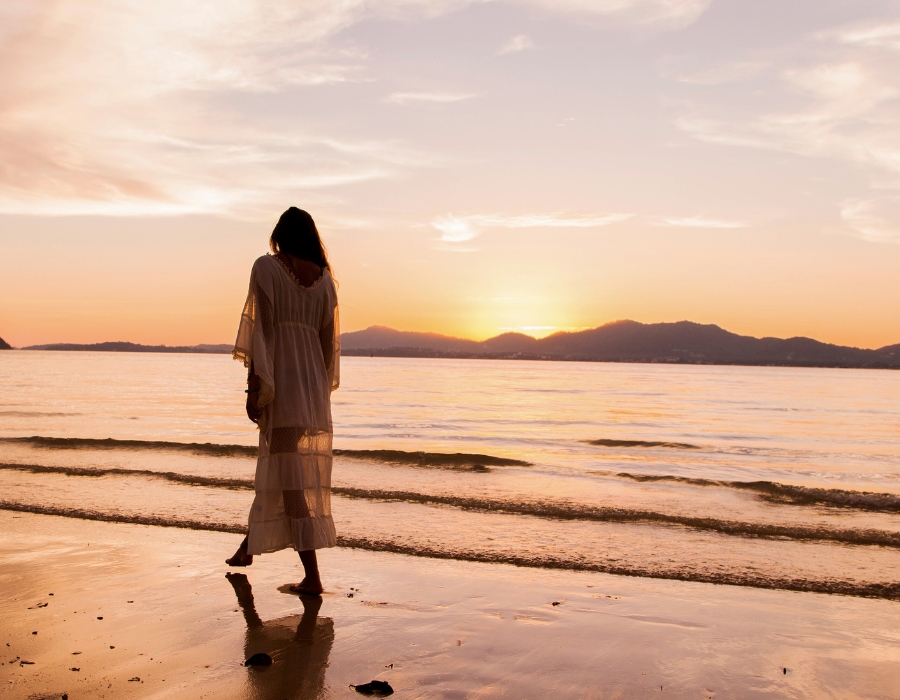 woman walking on beach at sunset